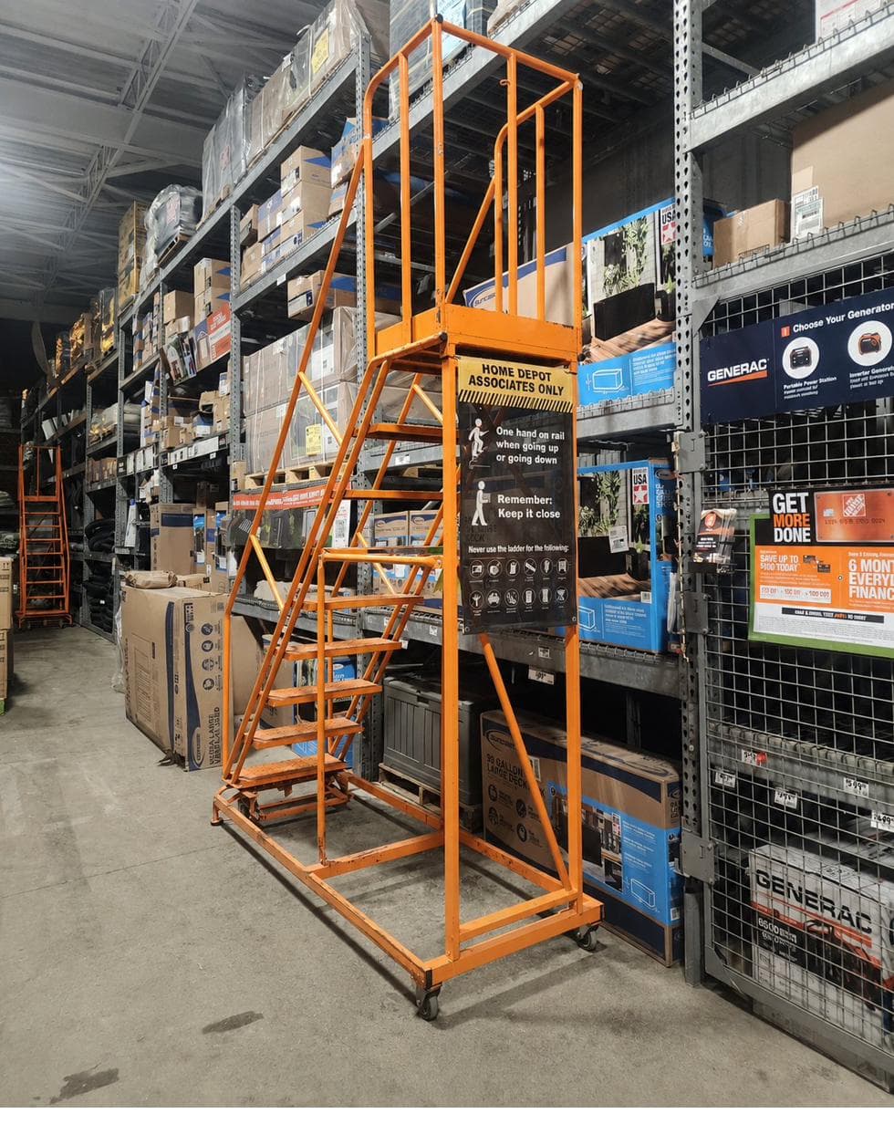 Orange associate-only rolling ladder in a Home Depot aisle