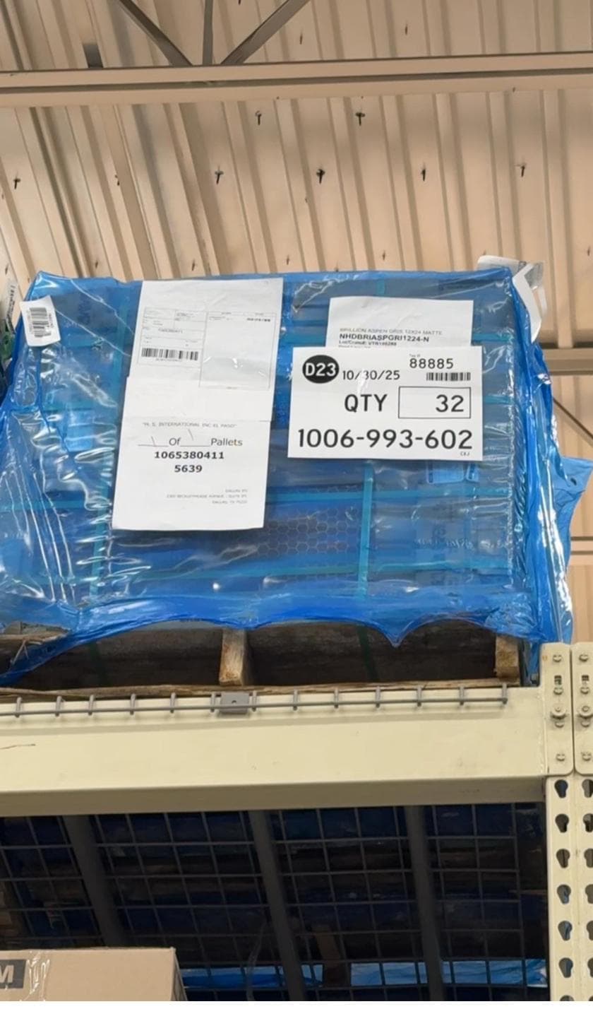 Shrink-wrapped pallet in a Home Depot overhead bay with a label reading QTY 32
